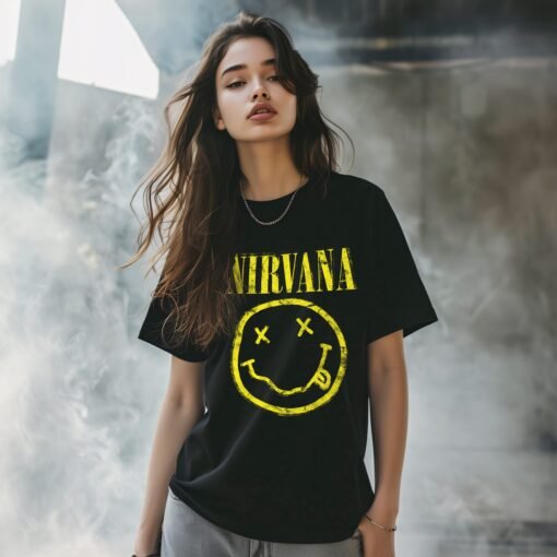 Nirvana Smiley Face T-shirt in vintage 90s grunge style, featuring the iconic yellow smiley logo and band name, associated with Kurt Cobain. Available in multiple colors like black, olive green, pink, charcoal, and plum. Casual unisex band tee, perfect for fans of Kurt Cobain, alternative fashion, and music merch.